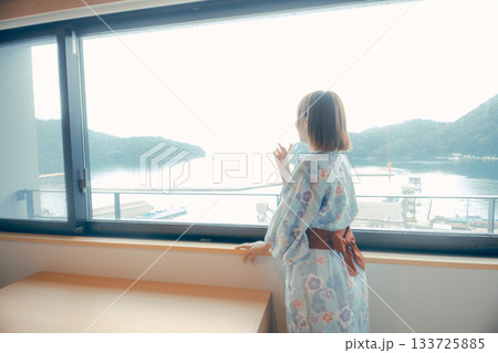 浴衣姿の20代女性がホテルの窓から景色を眺めるシーン 133725885