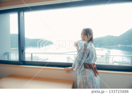 浴衣姿の20代女性がホテルの窓から景色を眺めるシーン 133725886