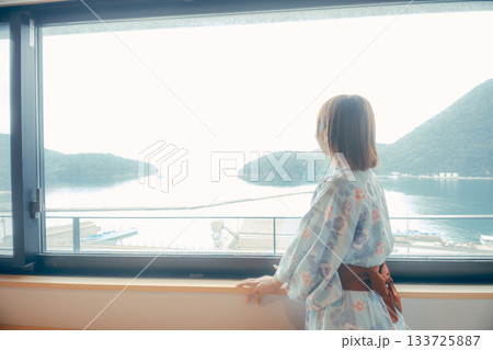 浴衣姿の20代女性がホテルの窓から景色を眺めるシーン 133725887