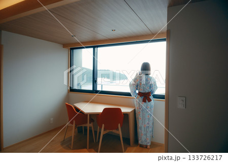 浴衣姿の20代女性がホテルの窓から景色を眺めるシーン 133726217