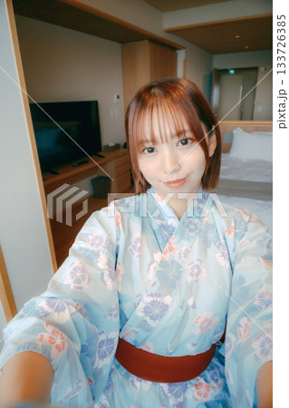 浴衣姿の20代女性が客室で自撮りをするシーン 133726385