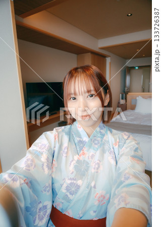 浴衣姿の20代女性が客室で自撮りをするシーン 133726387