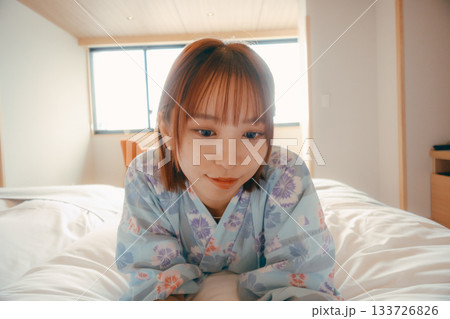 浴衣姿の女性がベッドでうつ伏せにくつろぐシーン 133726826