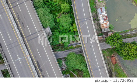 Aerial drone shot of a highway interchange overpass amidst lush green rice paddies and a river, showcasing infrastructure in nature. 133726958