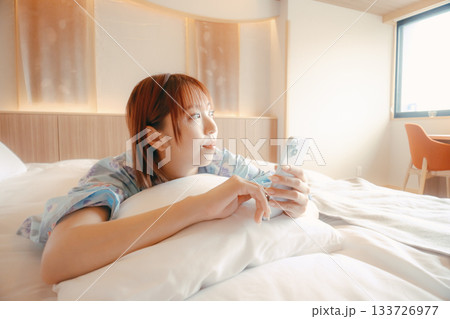 浴衣姿の女性がベッドでくつろぐシーン 133726977