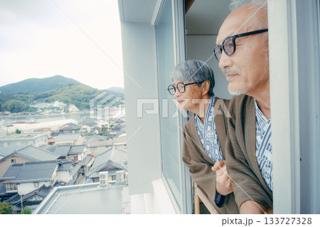 浴衣姿の高齢夫婦が窓辺から町並みを眺めるシーン 浴衣姿の高齢夫婦が窓辺から町並みを眺めるシーン 133727328