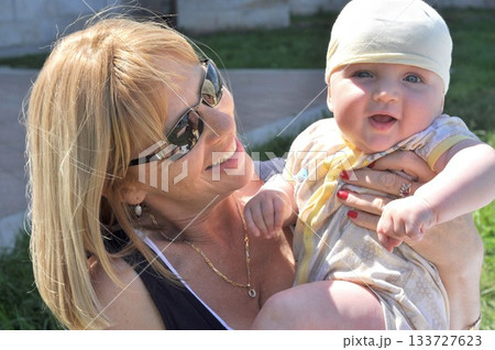 Grandmother Joyfully Holding Smiling Grandson Outdoors Grandmother Joyfully Holding Smiling Grandson Outdoors 133727623
