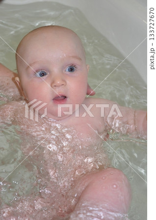 Baby Bathing in Bathtub with Curious Expression 133727670