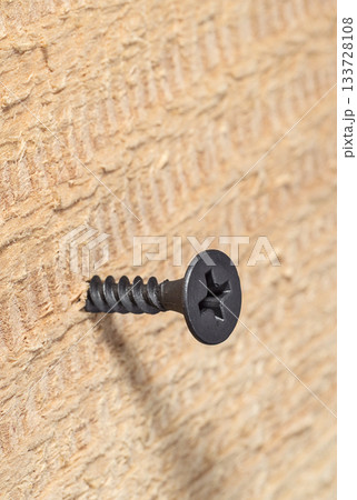 Dark  screw screwed into wooden wall 133728108