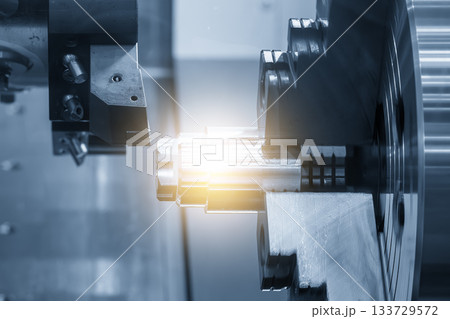 Close up scene the CNC lathe machine finish cut the metal shaft parts in the blue tone scene with lighting effect. Close up scene the CNC lathe machine finish cut the metal shaft parts in the blue tone scene with lighting effect. 133729572