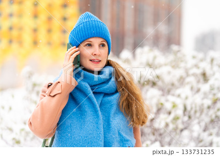 Woman in a coat talking on the phone 133731235