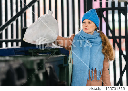 Young woman goes for a walk in the yard and takes out the trash 133731236