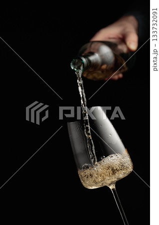 Pouring white wine in a glass goblet. Pouring white wine in a glass goblet. 133732091