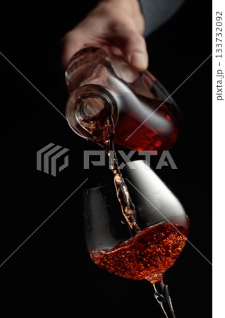Pouring brandy in a glass goblet. Pouring brandy in a glass goblet. 133732092