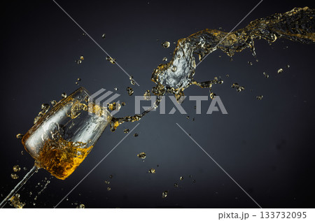 Glass and white wine splash on a black background. Glass and white wine splash on a black background. 133732095