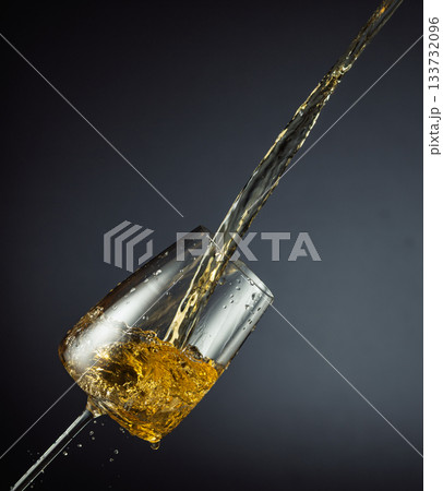 Glass and white wine splash on a black background. Glass and white wine splash on a black background. 133732096