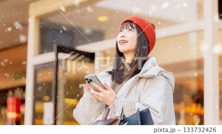 雪の降る冬の街角でスマートフォンを使う女性 雪の降る冬の街角でスマートフォンを使う女性 133732426