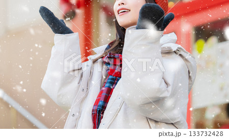 雪の降る冬の街角に立つ笑顔の女性 133732428