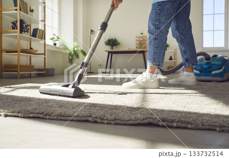 Cropped photo of woman cleaning with vacuum cleaner carpet in the living room at home. 133732514