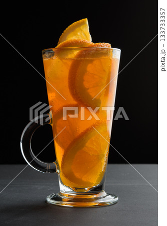 A drink with orange slices in a tall glass on a black table A drink with orange slices in a tall glass on a black table 133733357