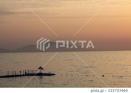 Early morning over the Red Sea. The water surface is covered with smoke and the orange color of the sunrise. In the foreground is a plastic yacht marina. Winter sea beach pier rocks 133733460