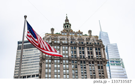 American flag at modern building in metropolis city. Business building skyscraper in city. City downtown with skyscraper. Architecture. Skyscraper building architecture. American flag, copy space American flag at modern building in metropolis city. Business building skyscraper in city. City downtown with skyscraper. Architecture. Skyscraper building architecture. American flag, copy space 133733587
