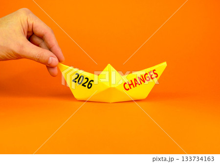 2026 Changes symbol. Concept words 2026 Changes on beautiful yellow paper boat. Beautiful orange paper background. Businessman's hand. Business and 2026 changes concept. Copy space. 2026 Changes symbol. Concept words 2026 Changes on beautiful yellow paper boat. Beautiful orange paper background. Businessman's hand. Business and 2026 changes concept. Copy space. 133734163