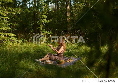 Sunlit meadow scene with woman leisurely reading and turning pages 133734250