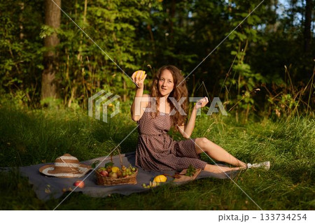 Peaceful environment where woman is delighting in her apple outdoors 133734254