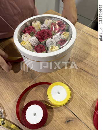 Woman packing homemade marshmallow in a hat box with transparent lid, Marshmallow flowers, tulips and roses, Packaging ribbons nearby 133734447