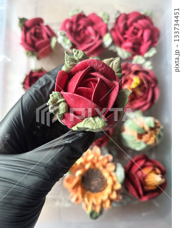 Hand in a rubber glove holding a marshmallow rose, Homemade marshmallow, Marshmallow flowers, Marshmallow roses, tulips and sunflowers are arranged in the background Hand in a rubber glove holding a marshmallow rose, Homemade marshmallow, Marshmallow flowers, Marshmallow roses, tulips and sunflowers are arranged in the background 133734451