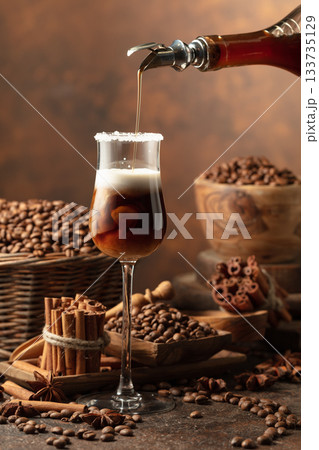 Coffee liqueur is poured from a bottle into a glass with cream. Coffee liqueur is poured from a bottle into a glass with cream. 133735129