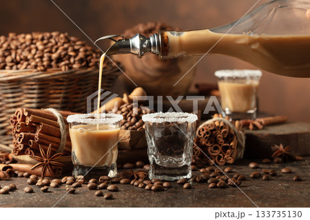 Irish cream and coffee liqueur is poured from a bottle into a glass. Irish cream and coffee liqueur is poured from a bottle into a glass. 133735130