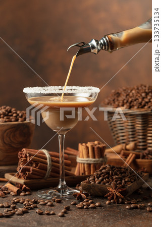 Chocolate martini cocktail or Irish cream liquor is poured from a bottle into a glass. Chocolate martini cocktail or Irish cream liquor is poured from a bottle into a glass. 133735134