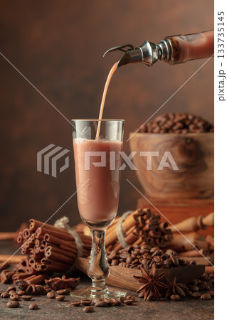Irish cream and coffee liquor is poured from a bottle into a glass. 133735145