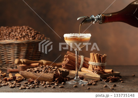 Coffee liqueur is poured from a bottle into a glass with cream. Coffee liqueur is poured from a bottle into a glass with cream. 133735148