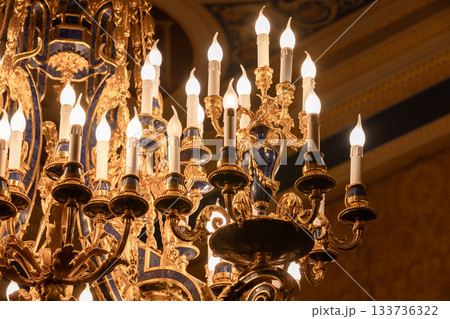 A majestic gilded chandelier with candle-style bulbs, blue ceramic accents A majestic gilded chandelier with candle-style bulbs, blue ceramic accents 133736322