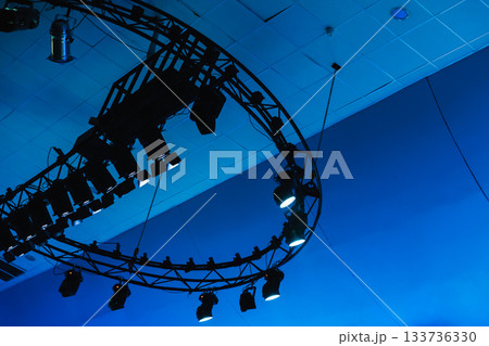 A circular truss lighting rig suspended from the ceiling casts blue tones A circular truss lighting rig suspended from the ceiling casts blue tones 133736330