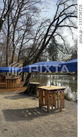 Calm Lakeside Park With Blue Umbrellas and Wooden Tables at Christmas Market in Bad Aibling 133736728