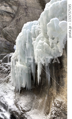 Frozen Icicle Cliff Partnachklamm: Dramatic Ice Formations Cascading Over Rugged Rock Wall by Water 133737595