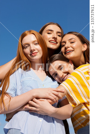 Group of Friends Enjoying a Sunny Day Outdoors With Blue Skies in a Casual and Joyful Moment 133737611