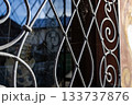 A close-up view of an old metal window grille with delicate spider webs catching the sunlight, creating a rustic and atmospheric detail of decay, texture, and quiet stillness. 133737876
