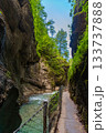 Narrow walkway carved into the cliffside along a turquoise stream inside Partnachklamm Gorge, Garmisch-Partenkirchen, Bavaria. A stunning natural passageway through dramatic alpine rock formations. 133737888