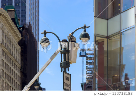 Streetlight maintenance taking place in busy urban area with tall buildings 133738188