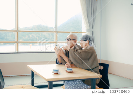 旅館の和室でスマホを一緒に眺める高齢夫婦 旅館の和室でスマホを一緒に眺める高齢夫婦 133738460