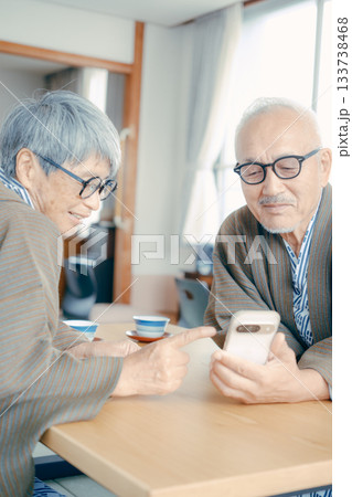旅館の和室でスマホを一緒に眺める高齢夫婦 旅館の和室でスマホを一緒に眺める高齢夫婦 133738468