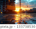 Excavator standing on a wet construction site at sunset with glowing reflections 133738530