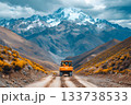Large construction truck driving along a dirt mountain road with dramatic peaks 133738533