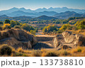 Open quarry site surrounded by autumn trees and layered mountain ranges under clear blue sky 133738810