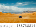Water transport truck driving across vast orange dunes toward distant mountains 133738814